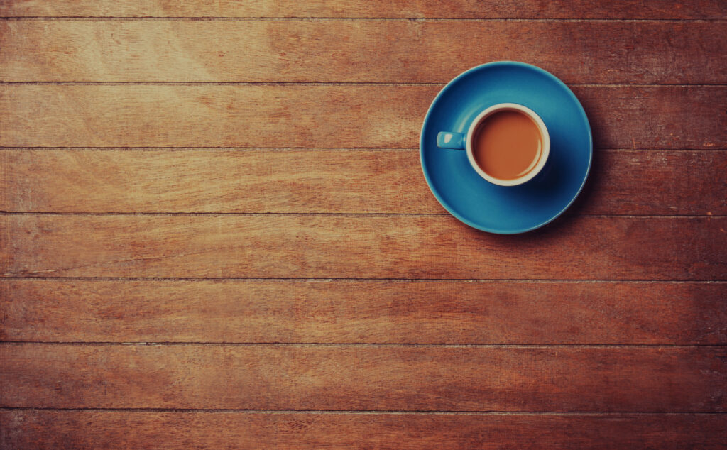Coffee cup on a blue saucer placed on a wooden table, enhancing a cozy atmosphere for digital marketing discussions.