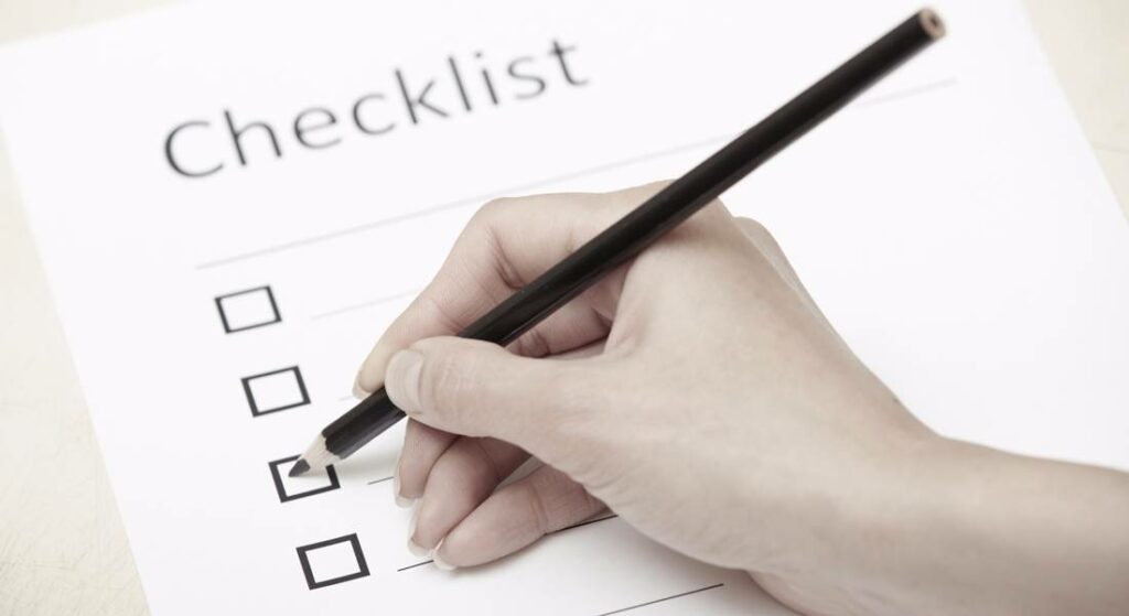 Checklist with a hand holding a pencil, emphasizing organization and planning in digital marketing strategies.