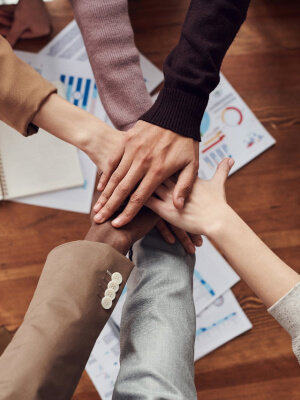 Diverse hands joining together over marketing strategy documents, symbolizing collaboration and partnership in digital marketing efforts.