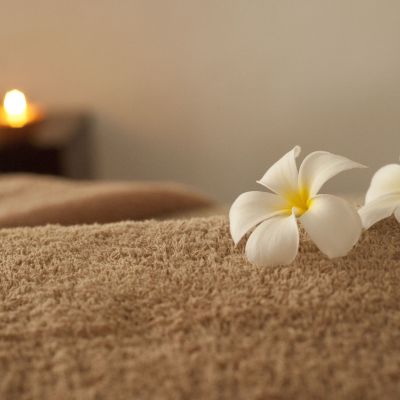 Spa treatment table with soft towel, white flowers, and warm candlelight, conveying a serene atmosphere for med spa services.
