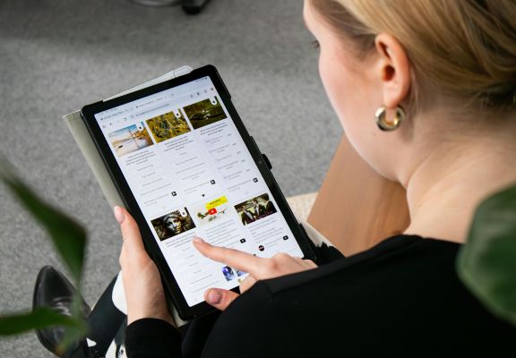 Woman using a tablet to curate content, engaging with social media management tools for audience interaction and brand visibility.