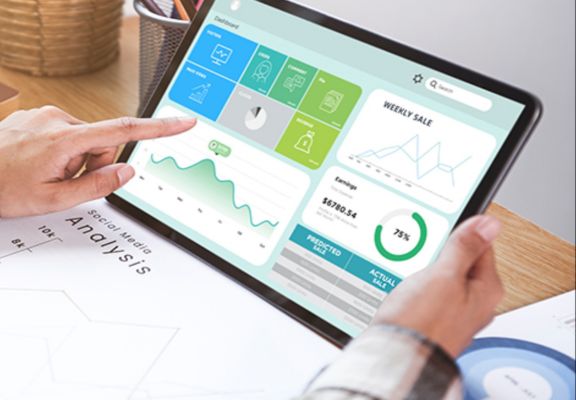 Person interacting with a tablet displaying digital marketing analytics and performance metrics, highlighting weekly sales and projected earnings, relevant to online growth strategy.