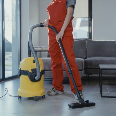 Person in red overalls using a yellow vacuum cleaner in a modern living room, emphasizing home cleaning services relevant to local SEO and lead generation for home service businesses.