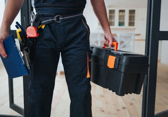 Person in work uniform holding a toolbox and clipboard, representing home service professionals like plumbers and electricians, emphasizing local visibility and trust in digital marketing strategies.