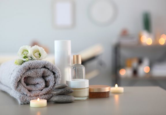Spa setting featuring rolled gray towel, skincare products, smooth stones, and lit candles, creating a tranquil atmosphere for medical spa services.