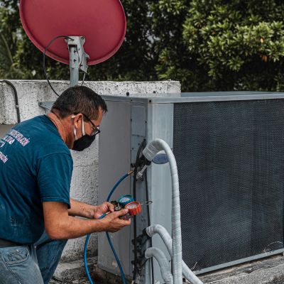 Technician servicing an air conditioning unit on a rooftop, demonstrating home service expertise relevant to urgent repair needs.
