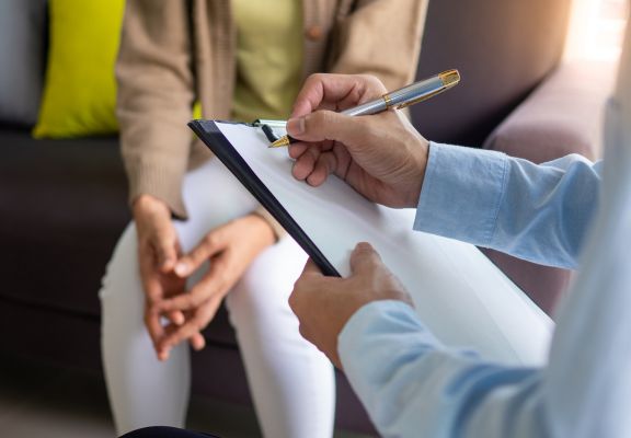Therapist taking notes during a session with a client, highlighting the importance of mental health support and professional connection.