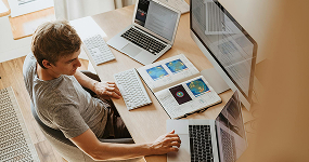 Person working at a desk with multiple laptops and documents, illustrating the importance of effective Local SEO strategies for business optimization and engagement.